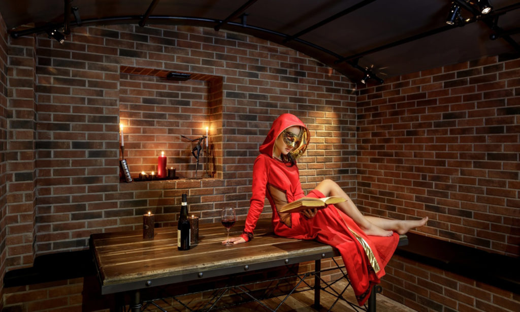 KinkBnB: Cloaked woman in dining alcove at Great Place Where The Dreams Can Come Truth