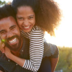 First Date couple smiling, woman riding piggyback on man