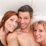 Open relationship two women and one man in bed